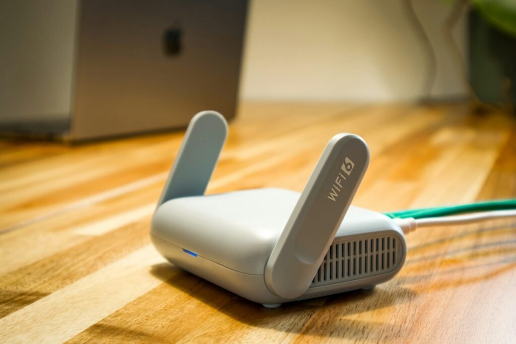 Modern Wi-Fi router with dual antennas on a wooden desk in a home office